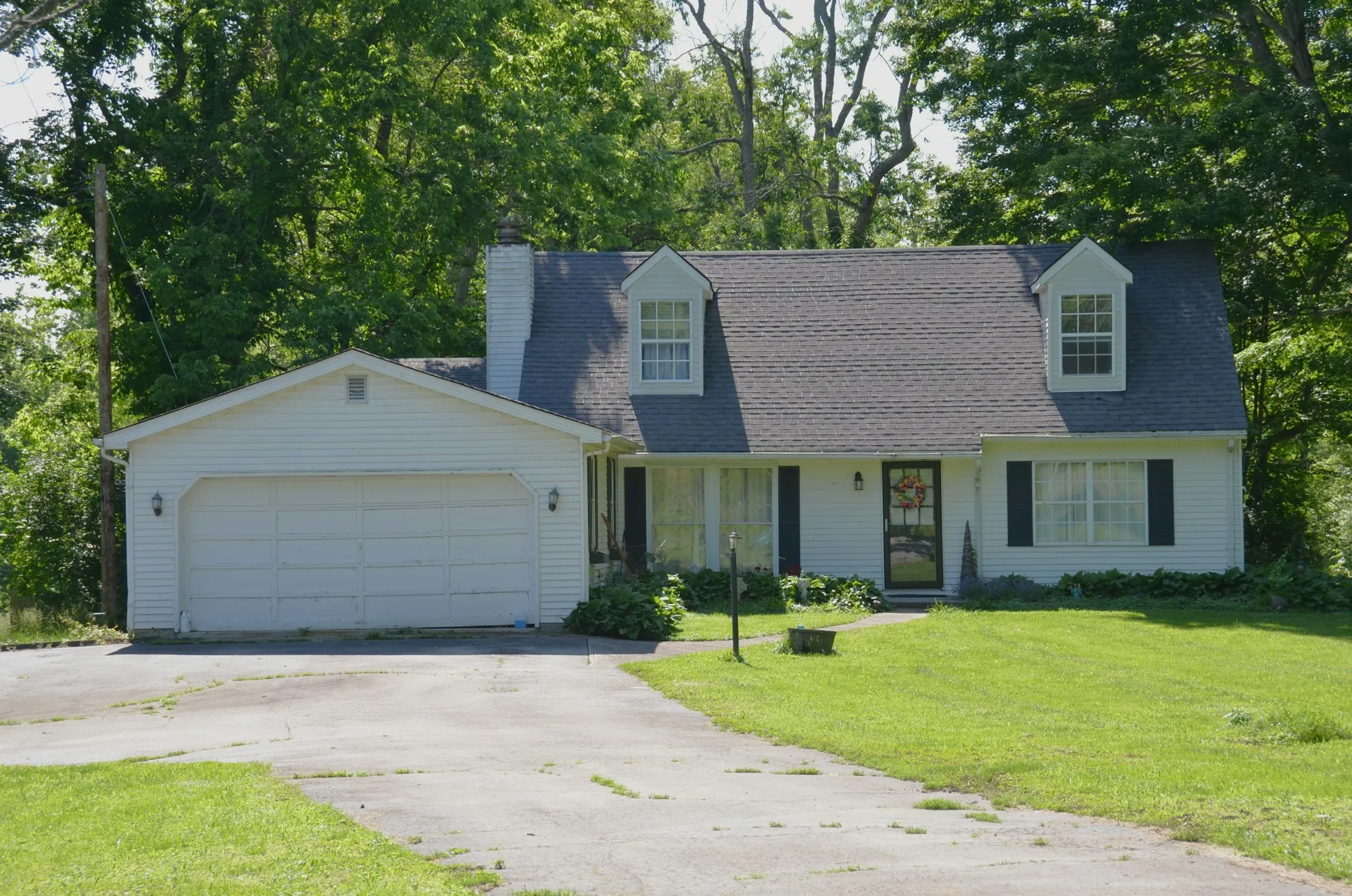 Cape Cod style home with a garage and long driveway