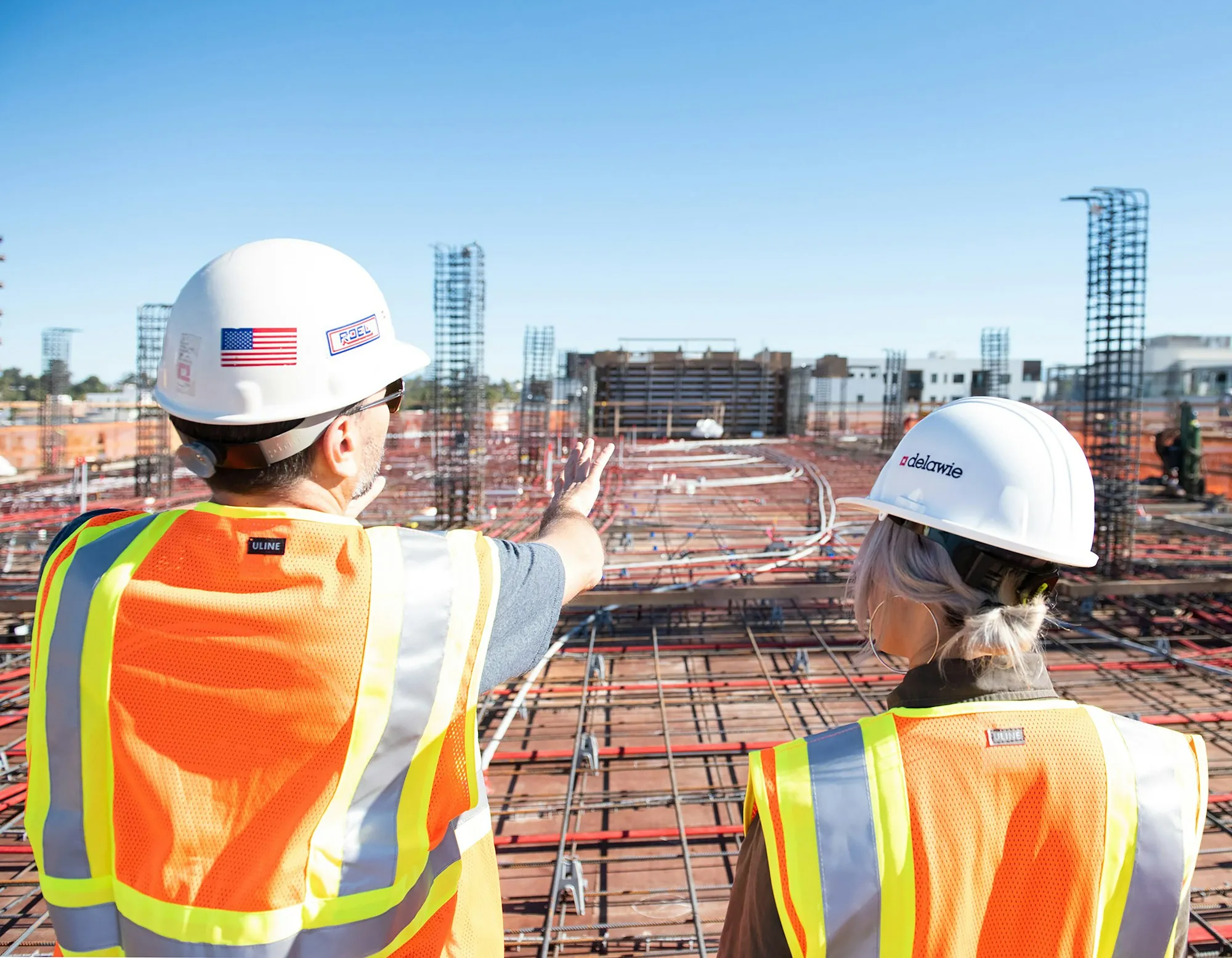 Workers in hard hats reviewing a rebar-covered site